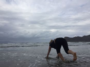 Full length of woman standing on beach against sky