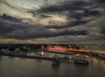 Illuminated bridge over river against sky in city