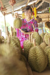 Portrait of smiling woman holding durian at store