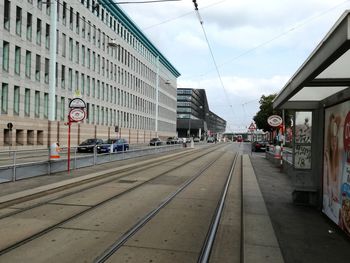 Railroad tracks by buildings in city against sky