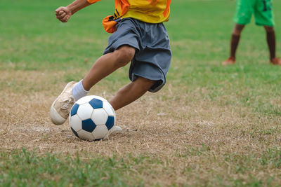 Low section of man playing soccer on field