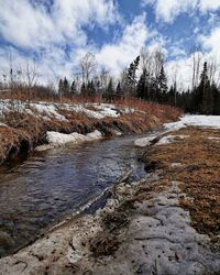Scenic view of stream against sky during winter
