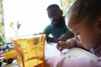 Girl drawing butterfly on paper by father at home