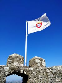 Low angle view of flag flying against clear blue sky