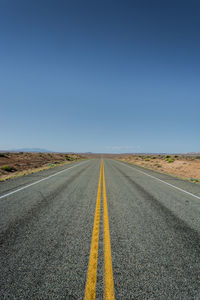 Road passing through landscape against clear sky