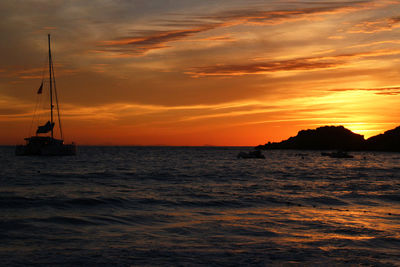 Sailboat sailing on sea against orange sky