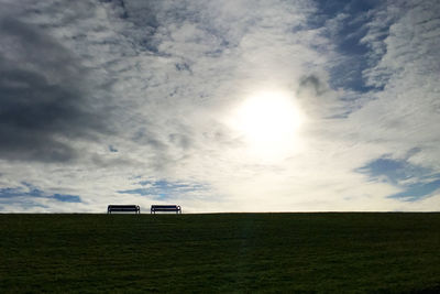 Scenic view of grassy field against cloudy sky