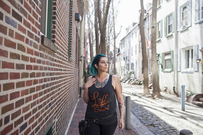 Full length of young woman standing on alley