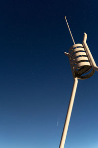 Low angle view of communications tower against clear blue sky