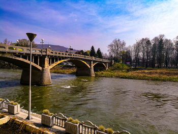 Arch bridge over river against sky