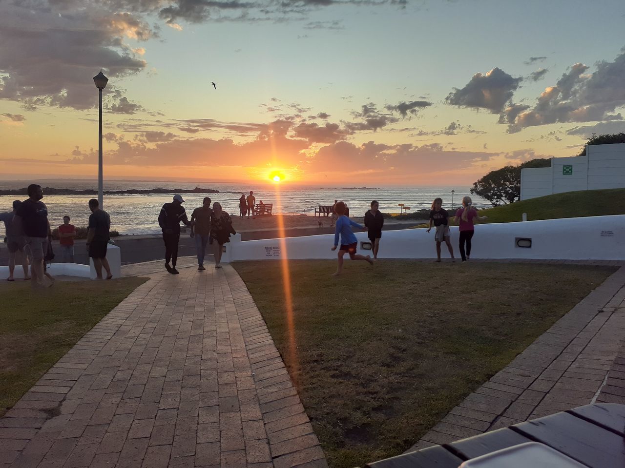 sunset, sky, water, sea, group of people, beach, nature, land, sun, horizon, cloud, coast, large group of people, evening, beauty in nature, crowd, travel destinations, travel, leisure activity, ocean, vacation, holiday, trip, scenics - nature, sunlight, lifestyles, men, adult, walkway, dusk, women, tourism, shore, outdoors, architecture, summer, walking, footpath