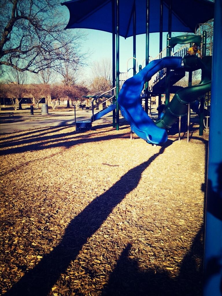 blue, shadow, sunlight, tree, playground, absence, empty, sand, built structure, outdoors, park - man made space, day, childhood, sunny, beach, incidental people, swing, bench, railing, street