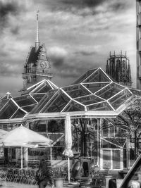 Low angle view of communications tower against cloudy sky