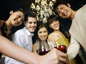 Low angle portrait of happy friends toasting wineglasses at party