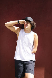 Young man wearing hat standing against wall