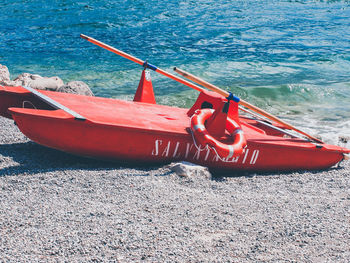 Red boat moored on beach against sky