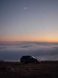 Car on land against sky during sunset