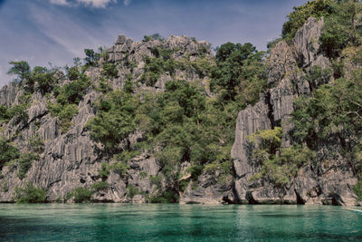 Scenic view of rocks by sea against sky