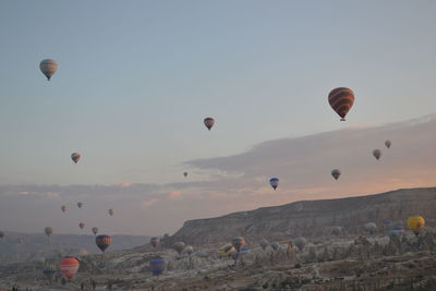 Hot air balloons flying over landscape against sky