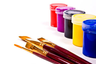 Close-up of paintbrushes and watercolor paints against white background