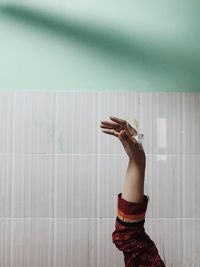 Midsection of woman with arms raised against wall