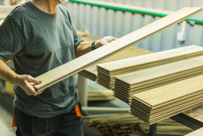 Worker working with planks in wood processing factory