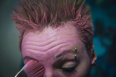 Cropped image of young woman applying make-up on face