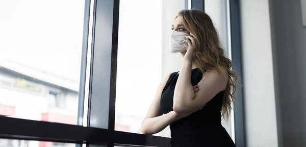 Side view of woman standing against window