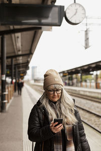 Young man using mobile phone at railroad station