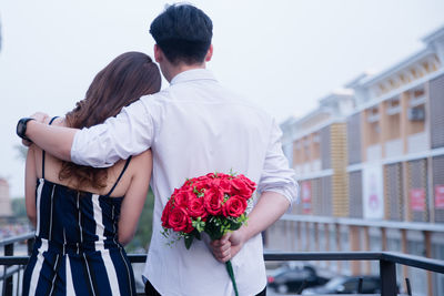 Rear view of man and woman holding red rose