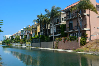 Swimming pool by houses against clear blue sky