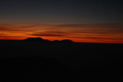 Scenic view of silhouette mountain against orange sky