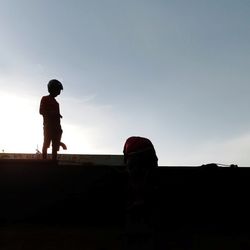 Silhouette men standing against sky