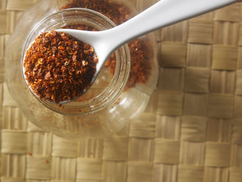 Directly above shot of chili flakes in glass jar bowl on table