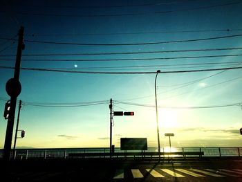 Low angle view of power lines against sky during sunset