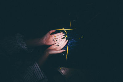 Cropped hands of woman holding star shape decorations in darkroom