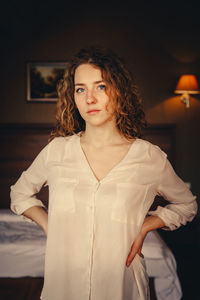 Portrait of young woman standing against wall