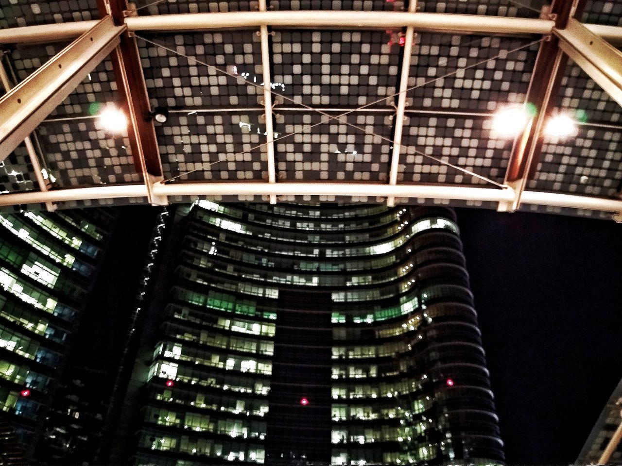 LOW ANGLE VIEW OF ILLUMINATED MODERN BUILDING AT NIGHT