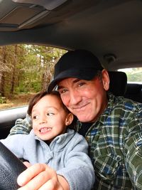 Portrait of smiling man with granddaughter sitting in car