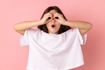 Portrait of young woman against pink background