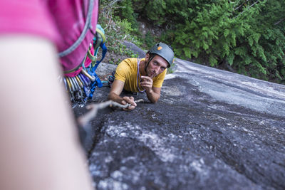 Man showing to shush and silence while poking climber with wood stick