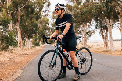 Woman standing with bicycle on road