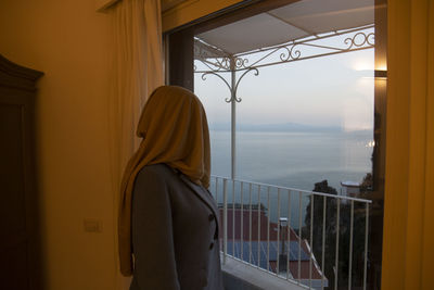 Rear view of woman looking through window