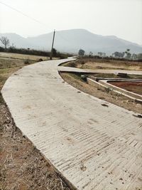 Road leading towards agricultural field against sky