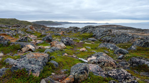 Scenic view of rocks by sea against sky