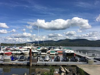 Boats moored at harbor against cloudy sky