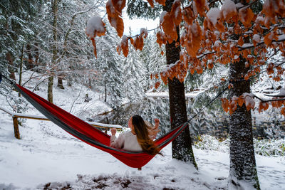 Woman resting in hammock on snow covered field