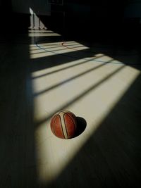 High angle view of ball on hardwood floor in darkroom