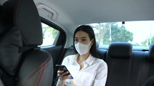 Portrait of young woman using smart phone in car