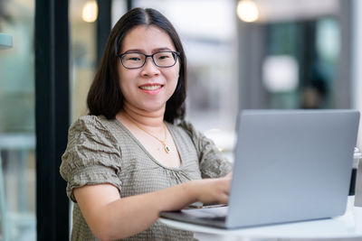 Portrait of young woman using laptop at cafe